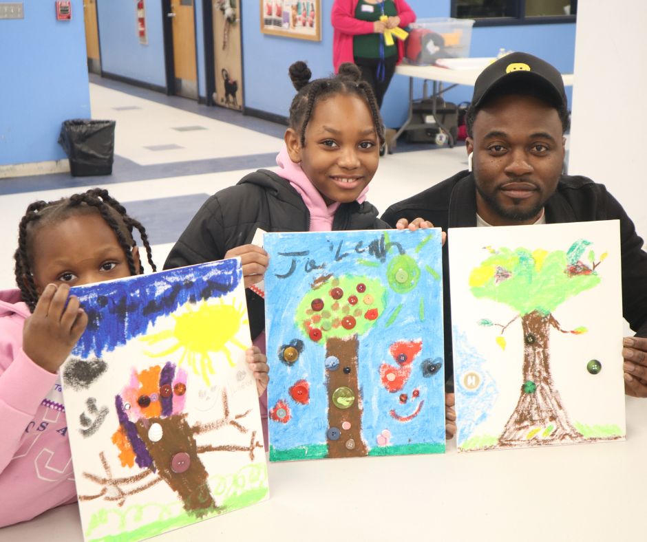 Family showing their art work at in-school Art in the Park 2024