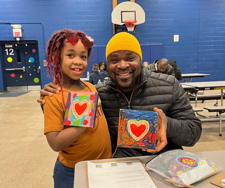 Father and daughter showing their art work at in-school Art in the Park 2024